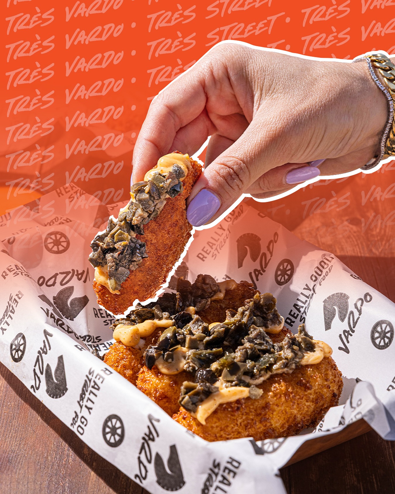 Crispy fried bites topped with orange sauce on branded Vardo paper